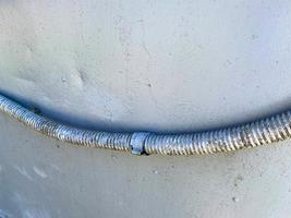 un cable eléctrico grande y grueso en una vaina corrugada sobre el fondo de una lámina de hierro azul. textura foto