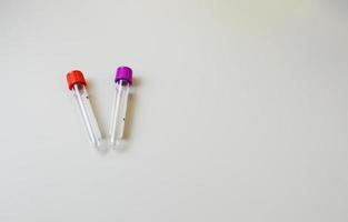 two test tubes with a red and purple cap on a white background. sterile, disposable tubes for venous blood collection. laboratory diagnostics, blood test from a vein photo