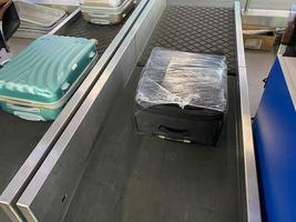 modern international airport interior view of baggage claim carousel and blue big travel bag with white sticker priority yellow label isolated on reclaim tape business air travel blurred background photo