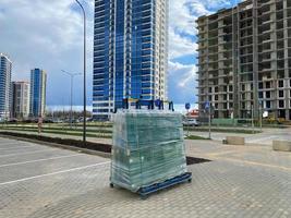 A large package of glass for windows of double-glazed windows wrapped with stretch film on the working site during the construction of houses photo