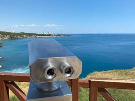 An observation deck on the embankment, equipped with a stationary viewing binoculars with a view of the sea and the seaport photo