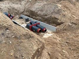Pipes in trench, industrial pipeline. Insulated pipes to connect a new buildings on heat system. One insulated pipe carries hot water, another carries cool water photo