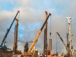 equipo de construcción en el sitio de reparación del paso elevado. grandes bloques de concreto son levantados por grúas y otros equipos de construcción. reparación del puente en el centro de la ciudad foto