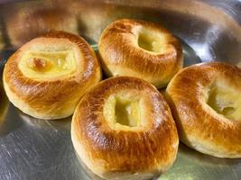 Freshly baked buns and tortillas lie on a baking sheet cut into pieces in a plate in a cafe or canteen photo