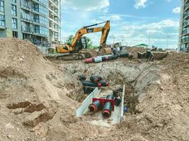 construction of a new area of the city. construction ditch, laying of cables and underground communications. burying large round pipes in the sand photo