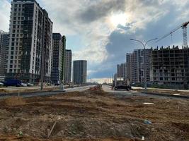 Construction of a wide high road in a new microdistrict of a large city with high-rise buildings and dense settlement photo
