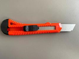 Red sharp office stationery knife with a paper cutting blade on a desktop office desk. Business work photo