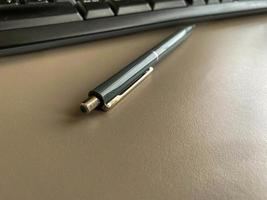 Automatic green ballpoint pen for writing on desktop office desk with computer keyboard. Business work photo