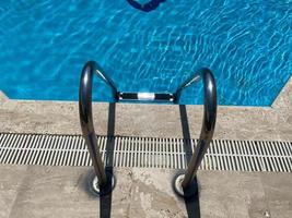 vista frontal de una escalera para entrar en un agua azul cristalina de la piscina foto