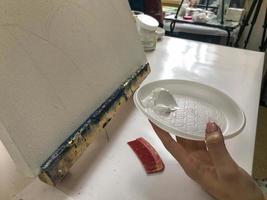 mujer pintora creando pintura abstracta acrílica fluida en clase de terapia de arte, dejando caer pinturas sobre lienzo foto