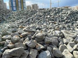 Large gray stones, rubble from industrial road construction and a view of new buildings with cranes at the construction site photo