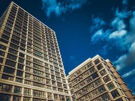 Two tall large new residential buildings skyscraper buildings built using monolithic-frame construction technology against the background of a blue sky photo