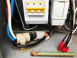 homemade electrical panel. gray meter with energy consumption indicator. thick wires for transmitting current. transfer of electricity between machines. automatic machines in yellow and blue photo