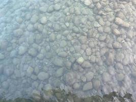 guijarros multicolores en la playa, bañados por olas foto