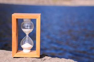 Wooden hourglass by the river photo