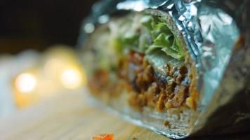 Very large burrito with avocado and chorizo meat. Filming in a romantic setting. Macro shooting video
