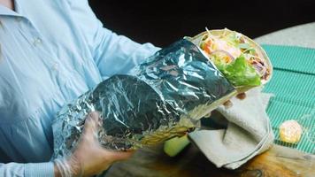 The chef arranges the aluminum foil in a very large burrito video