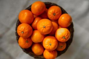 Basket with tangerine or orange fruit on a gray plaid background. photo