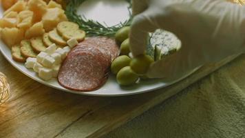 assiette de charcuterie avec salami, différentes sortes de fromages. il contient des fruits secs, diverses noix et du miel. arrangement de vacances avec des bougies allumées video