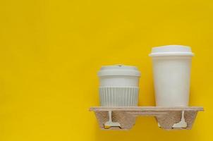 las tazas de café recicladas en la bandeja de papel de reutilización se colocan sobre fondo de papel amarillo para el concepto de medio ambiente mundial. foto