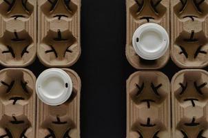 Two coffee tumblers on recycle paper trays put separate to each other with the gap. photo