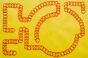 Las bandas de goma elásticas de color rojo se organizan en forma de línea sobre un fondo amarillo con un espacio vacío para el fondo y el concepto abstracto. foto