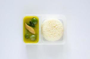 Top view of take away thai green curry with jasmine rice in plastic box on white background. photo