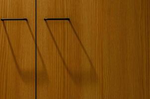 Wooden wardrobe and door handles with shadow for background photo. photo