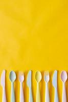 Colorful fork, spoon and knife on yellow background with empty space for text. photo