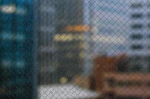 gota de lluvia en la ventana de vidrio en la temporada del monzón con fondo de edificios de la ciudad borrosa para el concepto abstracto y de fondo. foto