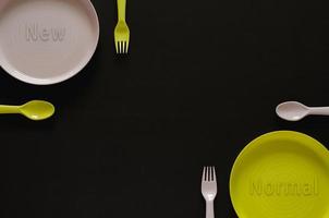 Colorful dish with fork and spoon put separate from each other on black background. photo