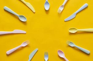 Colorful fork, spoon and knife on yellow background with empty space for text in the middle. photo