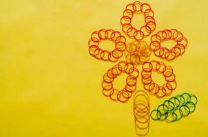 coloridas bandas elásticas de goma en forma de flor colocadas sobre fondo amarillo con espacio vacío para el fondo y el concepto abstracto. foto