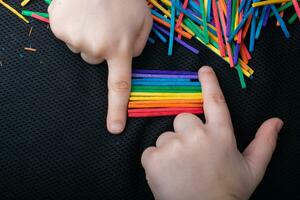 Kid playing with coloured wooden  sticks for creativity photo