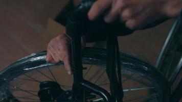 Side view of one American male workers in a workshop at a factory making wheelchairs, sitting at a workbench using hand tools and assembling parts of a product, sitting in wheelchairs video