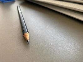 A simple black pencil lies sharply sharpened next to folders with sheets of paper and documents on the working business desk in the office. Stationery photo