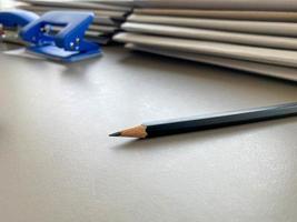 un simple lápiz negro se encuentra muy afilado junto a las carpetas con hojas de papel y documentos en el escritorio de trabajo de la oficina. papelería foto