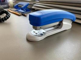 A large blue stapler for stapling paper lies next to the folders of documents on the working business desk in the office. Stationery photo