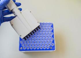 mechanical dispenser for setting test tubes in the hand of a doctor wearing a blue sterile glove. dispenser with multiple tips for easy analysis. laboratory diagnostics photo