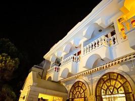 gran edificio blanco de dos plantas. zona hotelera en un balneario. descansar bajo el sol caliente y abrasador. el hotel tiene ventanas de vidrio con luz amarilla foto