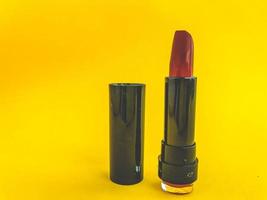 hermoso lápiz labial rojo glamoroso cosmético de belleza de moda para aplicar maquillaje en los labios sobre un fondo amarillo suave foto