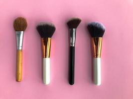 paintbrushes on a pink background. glamorous makeup artist table. brushes for applying powder, blush, foundation. natural bristle makeup brushes photo