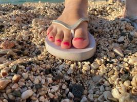 Womans feet with flip flops on the sand photo