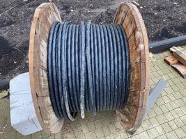 un grueso cable negro eléctrico enrollado en un gran rollo de madera se encuentra en un campo verde en la isla báltica de hiddensee. el cable debe tenderse bajo tierra foto