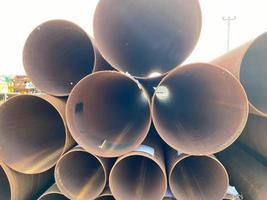 Lots of large diameter industrial iron rusty pipes with corrosion ready for installation plumbing for oil refinery petrochemical plant equipment at construction site photo