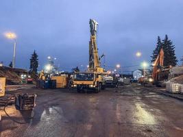 construction of a bridge in the city center. construction equipment is used to build a huge overpass from concrete blocks. people work on wet pavement photo