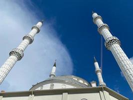 mezquita islámica nuevo árabe blanco moderno gran musulmán para rezar con una torre alta en un cálido complejo turístico del sur del país tropical oriental foto