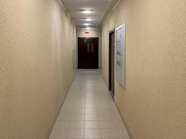 Long narrow yellow beige corridor with apartments in a new modern building photo