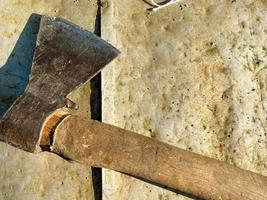 un viejo hacha de metal de hierro con un trasero y un hermoso mango oxidado y de textura para cortar leña, madera y árboles se encuentra sobre un fondo de hierro foto