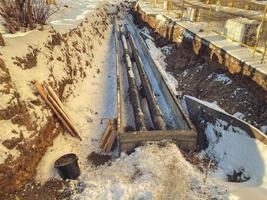 small, black, narrow pipes for laying plumbing communications. metal pipes under the snow. renovation work in a new residential area photo